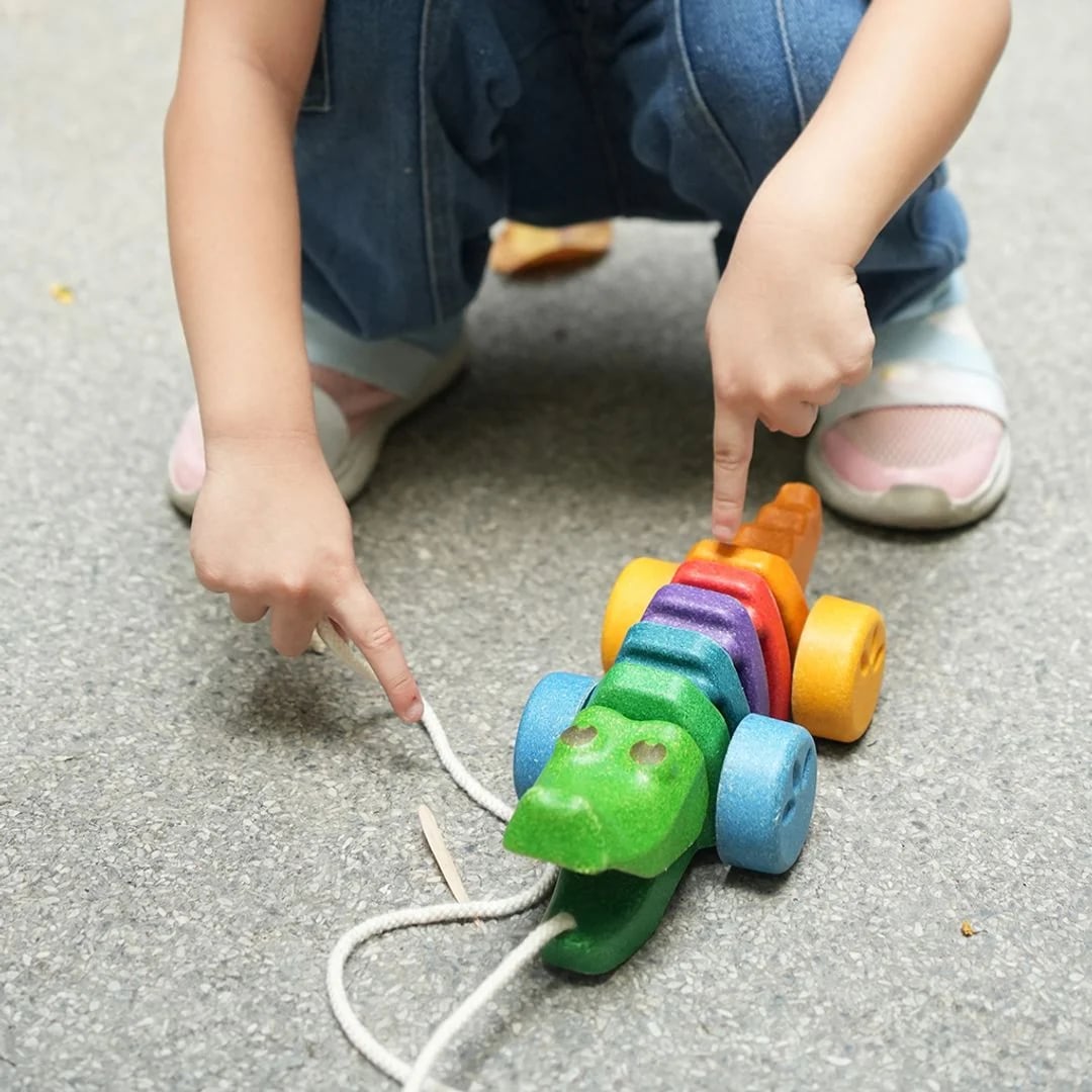 Dziecko trzymające zabawkę PlanToys Rainbow Alligator