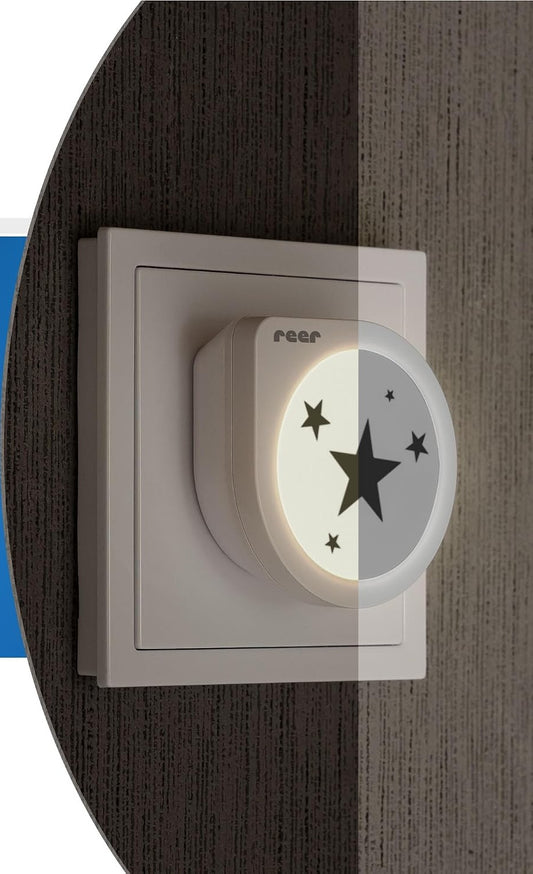 Lampka Reer NightGuide Star z podświetloną tarczą w gniazdku na ścianie.